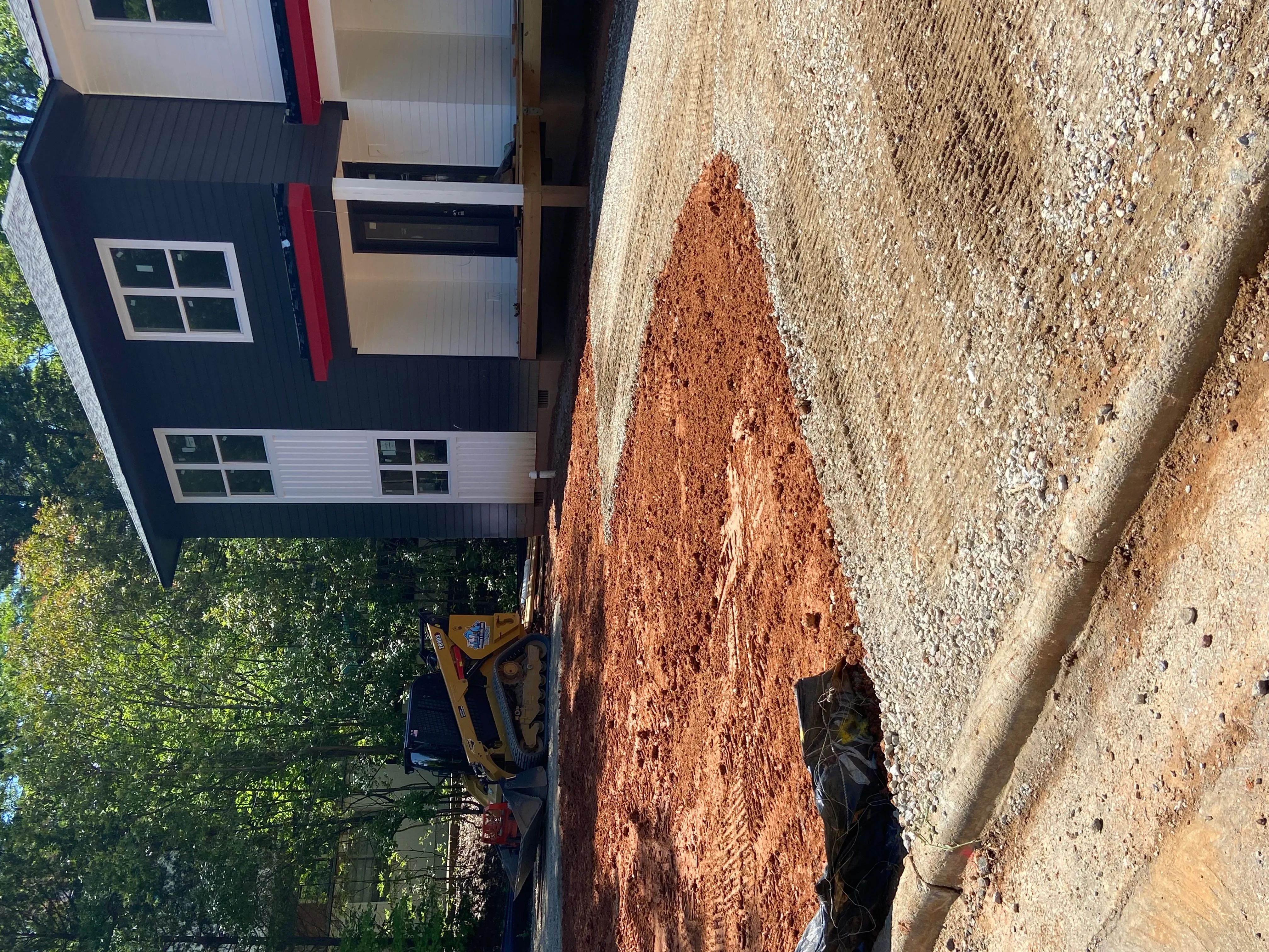 Residential driveway excavation with red clay base and gravel surface preparation