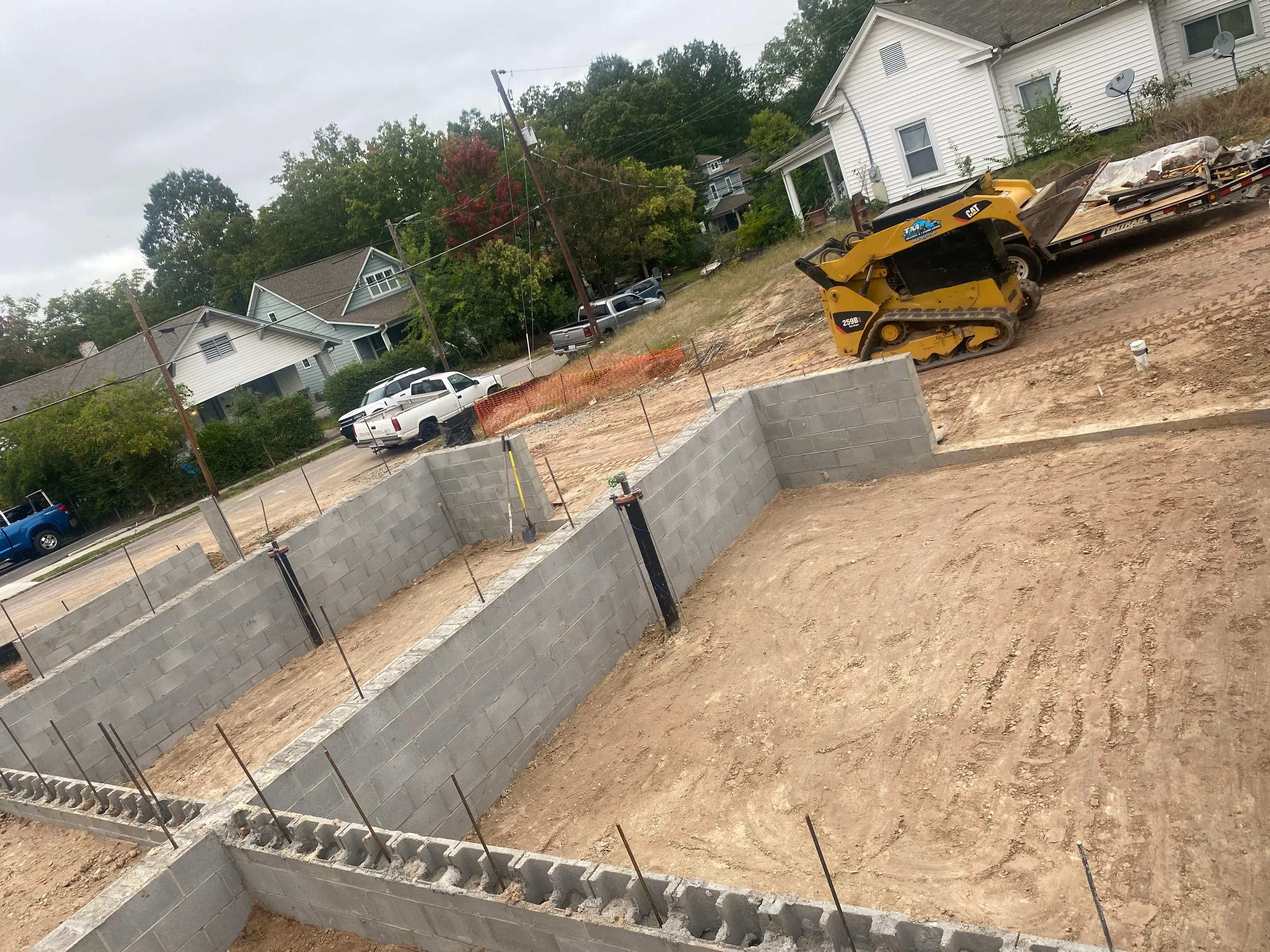 Concrete block retaining walls on excavated residential lot with compacted soil and grading equipment
