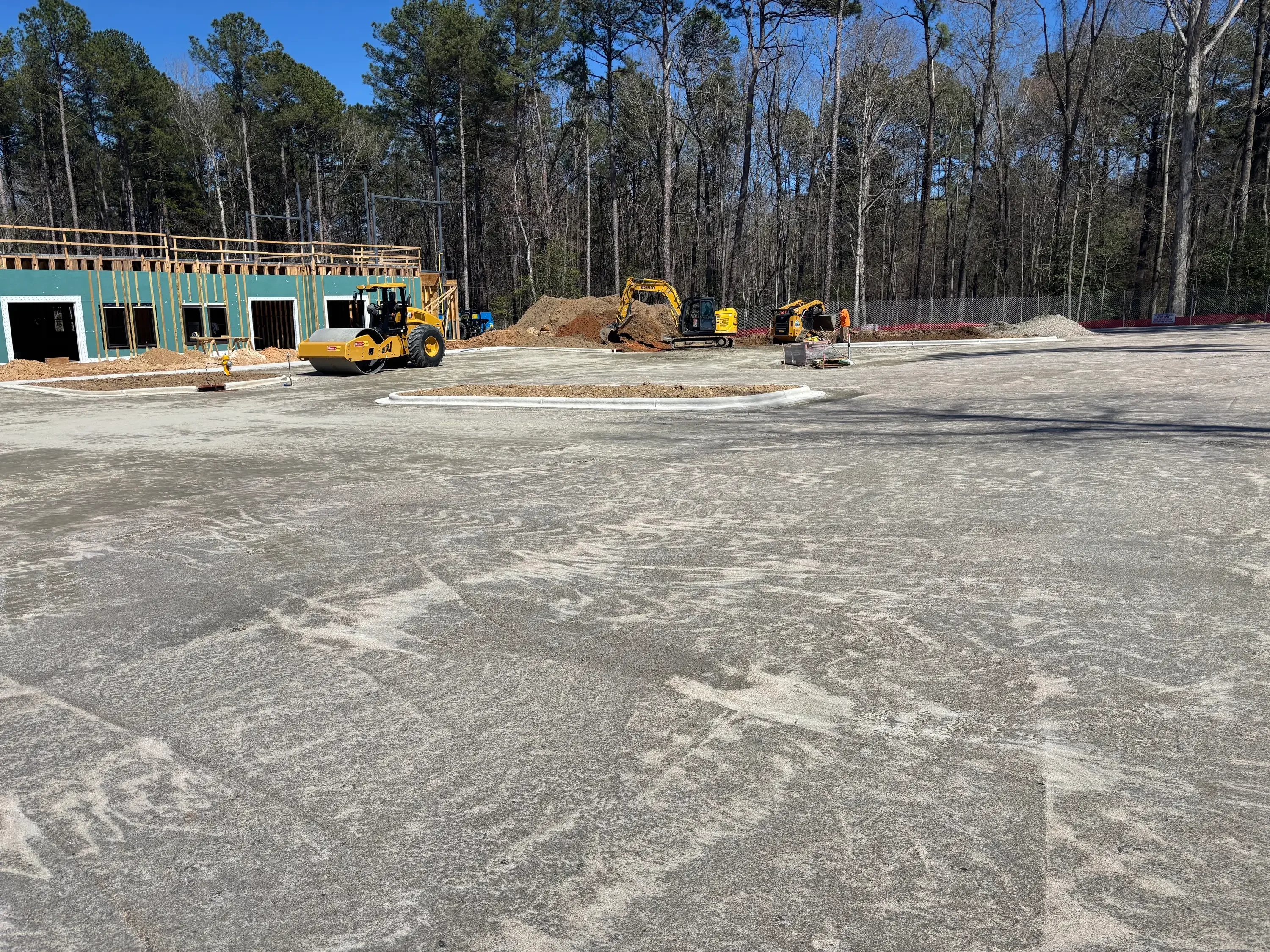 Concrete pad grading with wheel loader and mini excavator on commercial construction site
