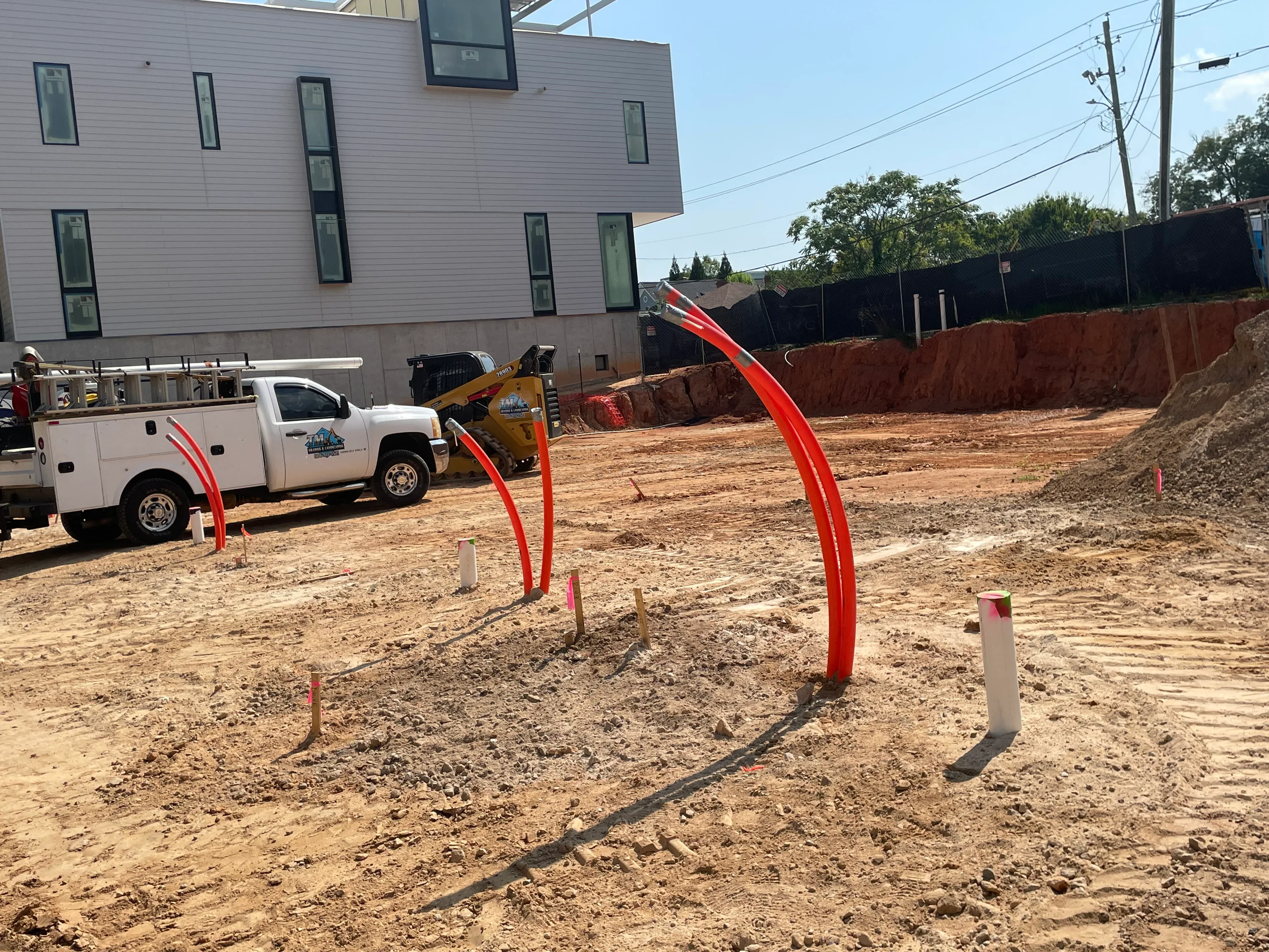 Excavated construction site with graded soil, red utility markers, and concrete grade stakes