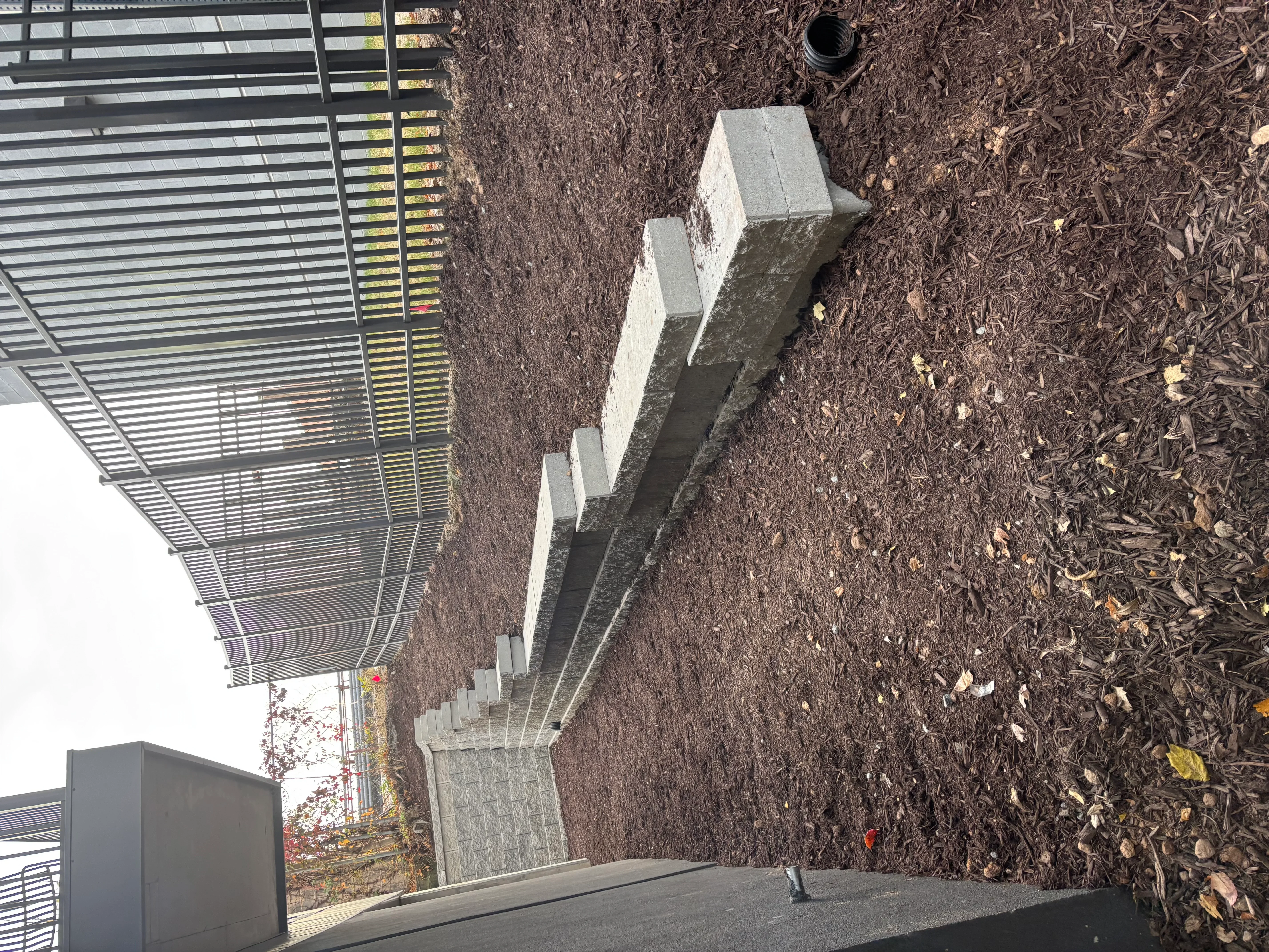 Concrete block retaining wall with drainage pipe and mulched landscape bed