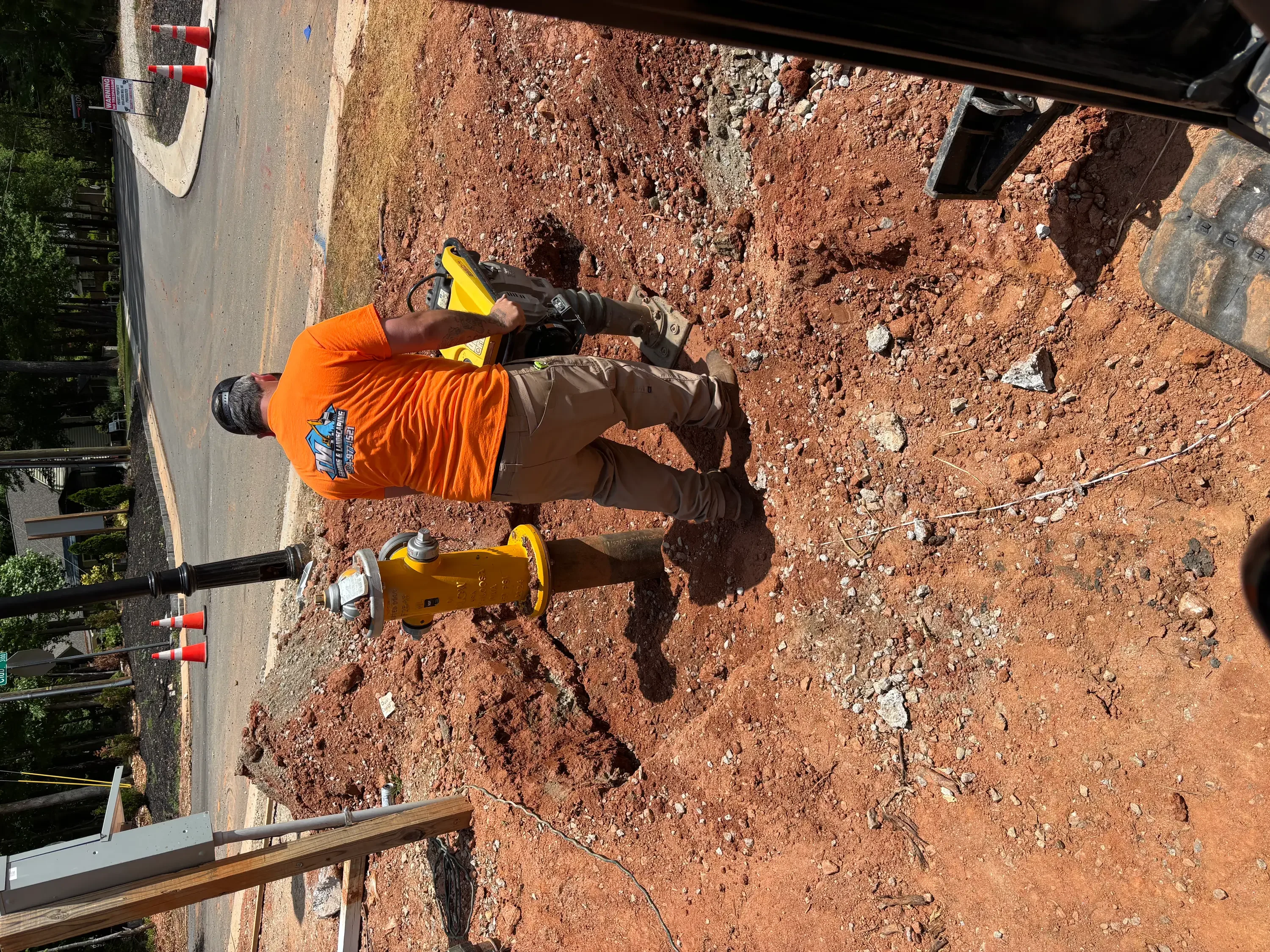 Worker with utility locating equipment on red clay soil excavation site