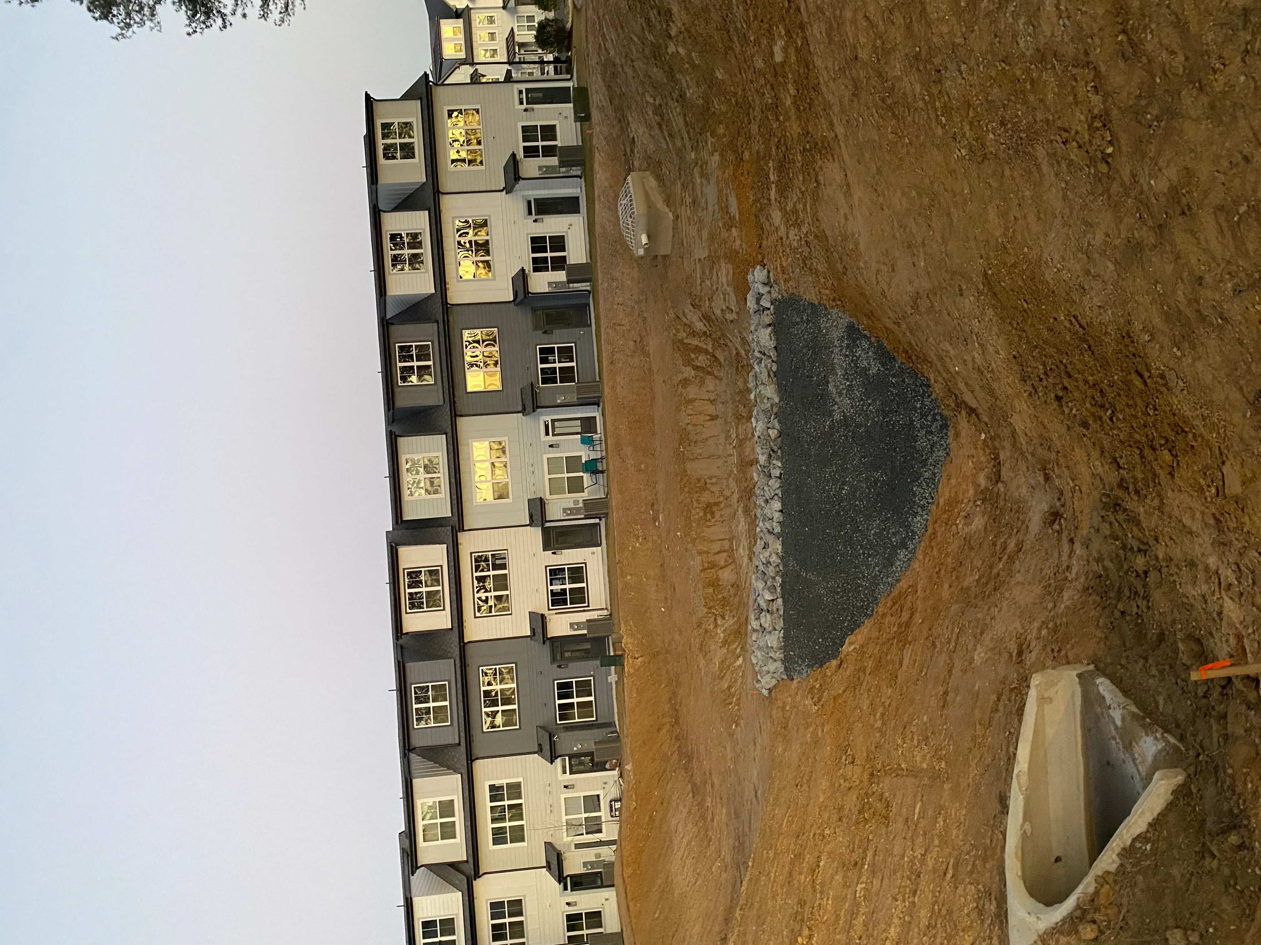 Newly paved asphalt driveway with compacted base material and residential buildings in background