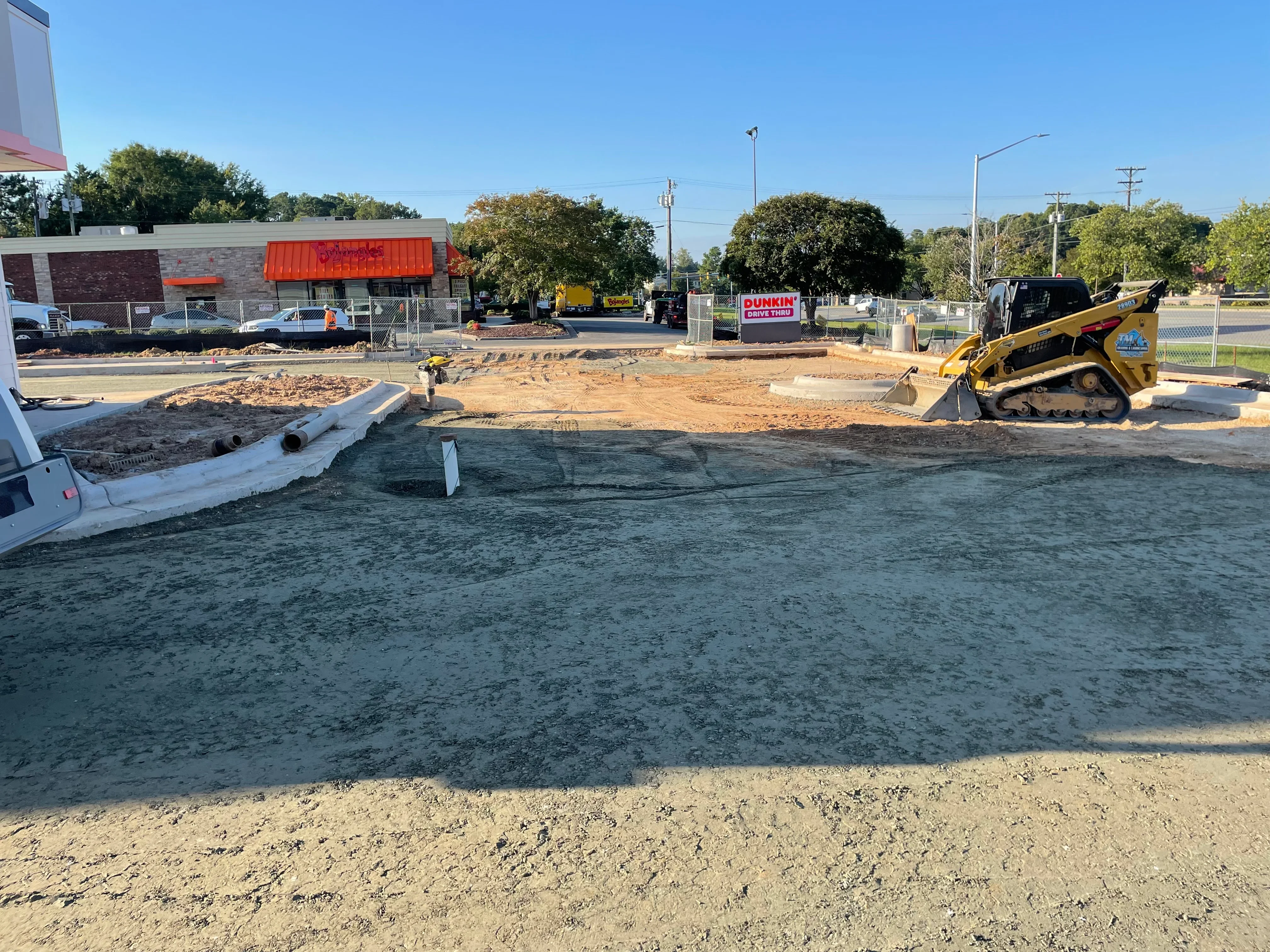 Excavated commercial lot with compacted asphalt base and grading equipment on-site