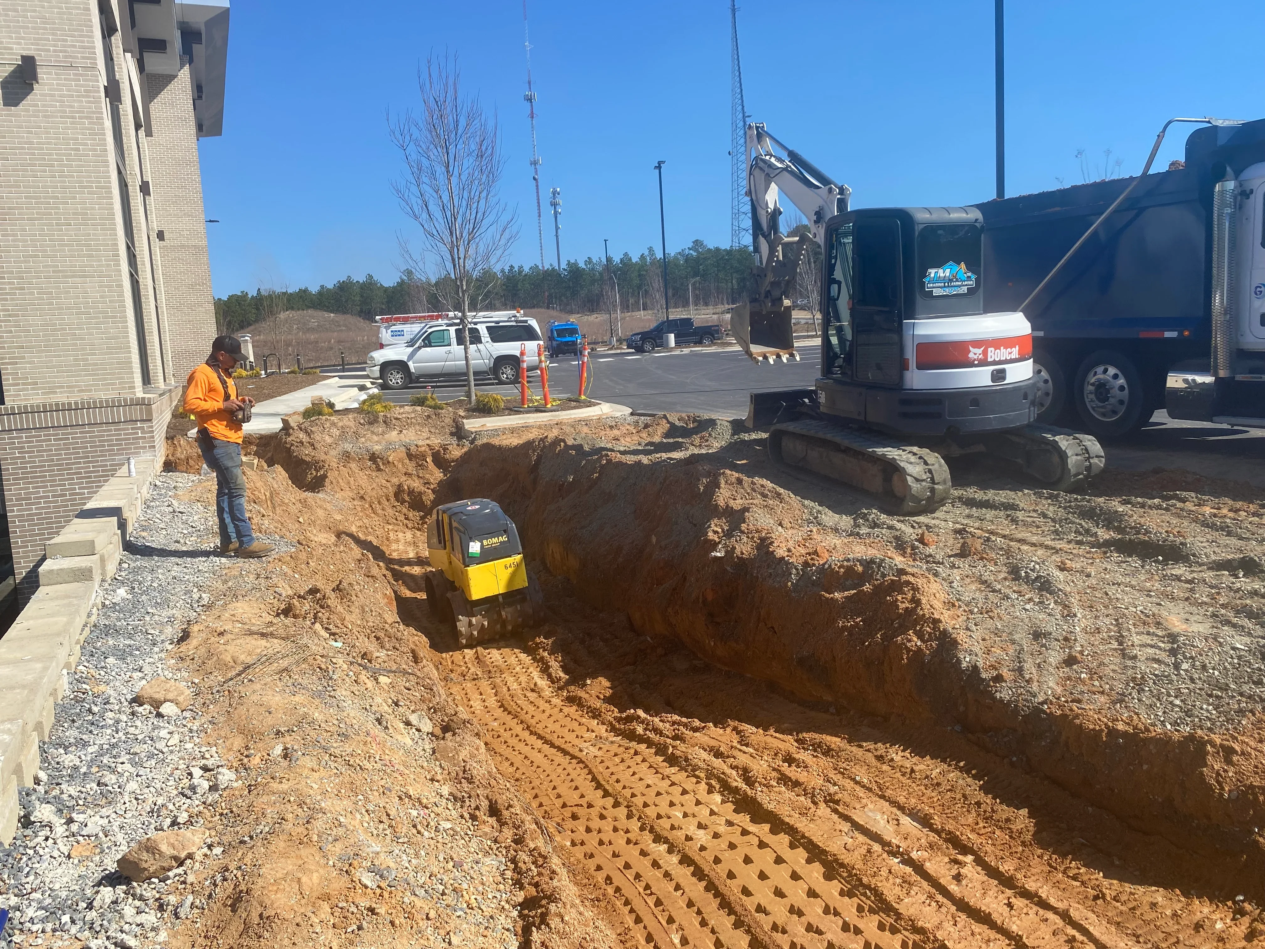 Excavation site with deep trench, compacted soil, erosion control matting, and heavy equipment